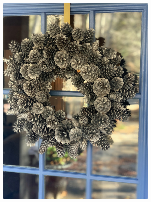 silver pinecone wreath on blue door